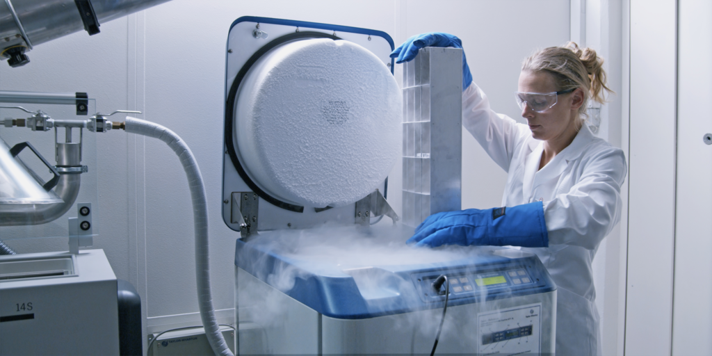 Laborant die een cryogene vriezer open doet